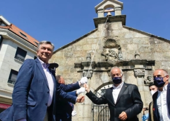 Yuri Korchagin, a la izquierda, hace sonar la campana junto al alcalde de Vilanova, Gonzalo Durán./ Foto: Mónica Irago / La Voz de Galicia