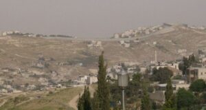 Vista del muro en Cisjordania con paisaje árido y edificaciones
