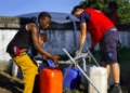 Personas llenando recipientes con agua potable en Mozambique tras inundaciones.