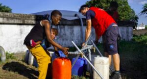 Personas llenando recipientes con agua potable en Mozambique tras inundaciones.