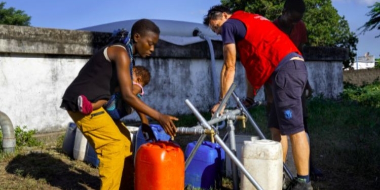 Personas llenando recipientes con agua potable en Mozambique tras inundaciones.