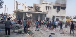 Escena de un ataque militar en Irán con edificios dañados y multitud de personas.