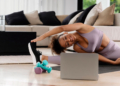 Mujer haciendo ejercicio en casa con mancuernas y computadora portátil