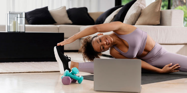 Mujer haciendo ejercicio en casa con mancuernas y computadora portátil