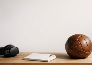 Pelota de fútbol y auriculares sobre una mesa de madera
