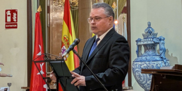 El embajador de Bulgaria hablando en un evento con banderas de España y Bulgaria.