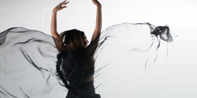 Mujer con velo negro danzando en un fondo blanco