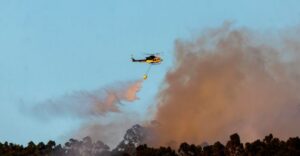 Helicóptero lanzando agua para apagar un incendio forestal