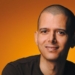 Retrato del escritor marroquí Abdellah Taïa con fondo naranja