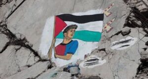 Mural de un joven sosteniendo una bandera palestina sobre escombros