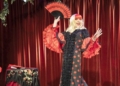 Artista drag con vestido de lunares y abanico en un escenario