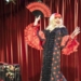 Artista drag con vestido de lunares y abanico en un escenario