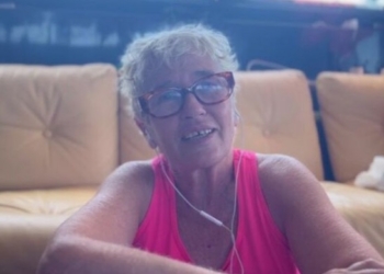 Alicia Armesto sonriendo mientras escucha música en un sofá