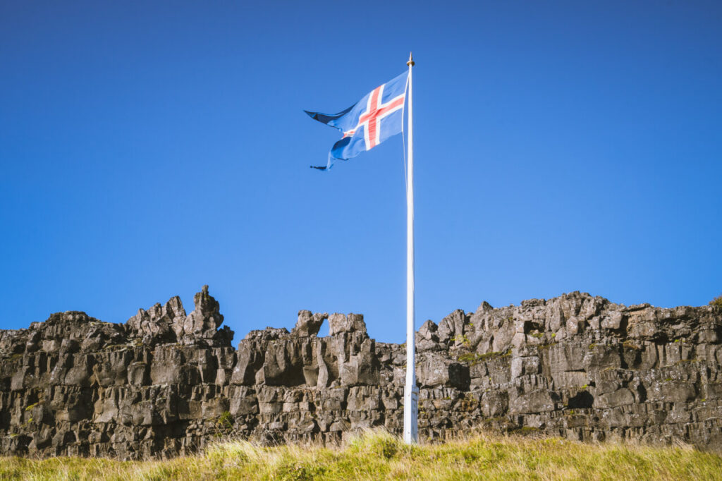 Bandera de Islandia ondeando contra un cielo azul claro.