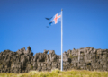 Bandera de Islandia ondeando contra un cielo azul claro.