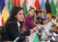 Mujeres en una mesa de diplomacia con banderas de varios países.