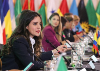 Mujeres en una mesa de diplomacia con banderas de varios países.