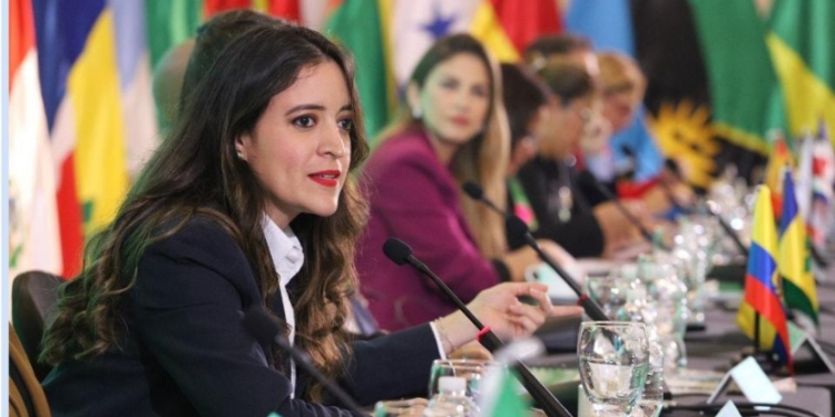 Mujeres en una mesa de diplomacia con banderas de varios países.