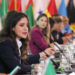 Mujeres en una mesa de diplomacia con banderas de varios países.