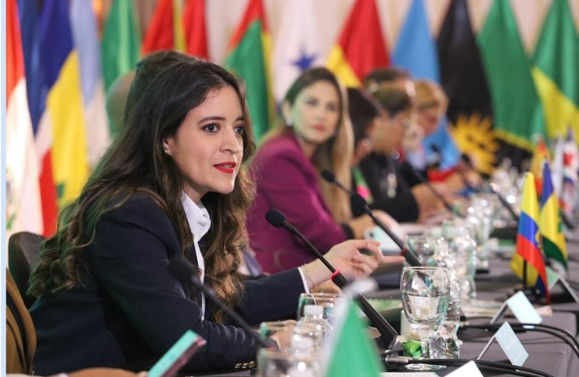 Mujeres en una mesa de diplomacia con banderas de varios países.
