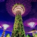 Vista nocturna de estructuras futuristas iluminadas con vegetación.
