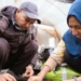Dos trabajadores en un entorno agrícola colaborando en una actividad de cultivo.