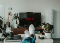 Persona relajándose en un sofá mientras ve Netflix en la televisión.