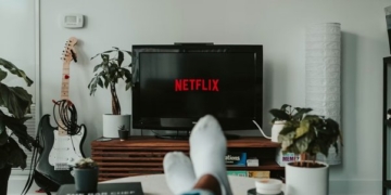 Persona relajándose en un sofá mientras ve Netflix en la televisión.