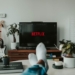 Persona relajándose en un sofá mientras ve Netflix en la televisión.