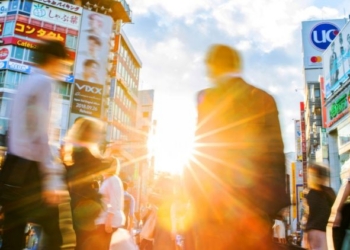 Personas caminando en una calle de Japón con anuncios y edificios