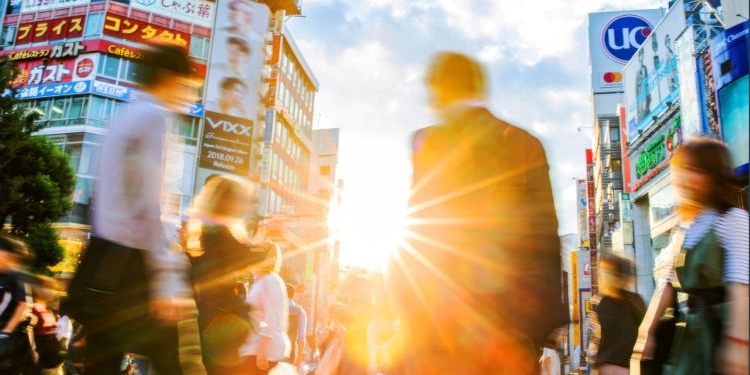 Personas caminando en una calle de Japón con anuncios y edificios