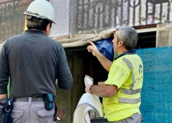 Dos trabajadores discutiendo en un sitio de construcción con señales de seguridad