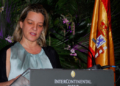 Ana Sálomon hablando en un evento oficial con la bandera de España de fondo