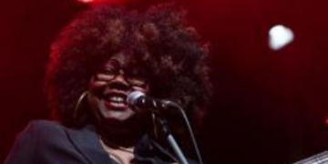 Manou Gallo sonriendo mientras toca el bajo en un concierto