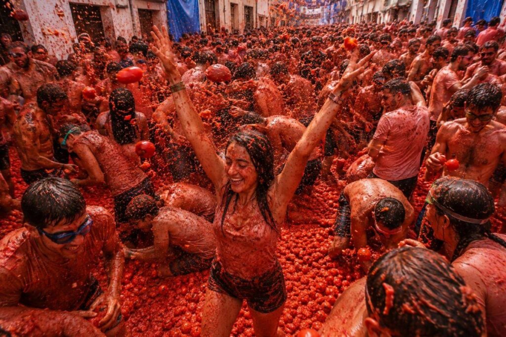 Participantes disfrutando de La Tomatina en Buñol, España, lanzando tomates.