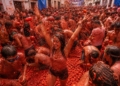 Participantes disfrutando de La Tomatina en Buñol, España, lanzando tomates.