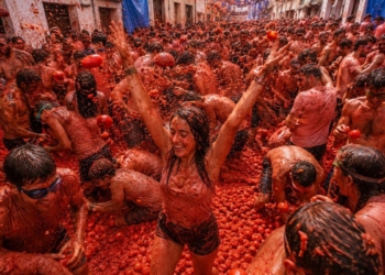 Participantes disfrutando de La Tomatina en Buñol, España, lanzando tomates.