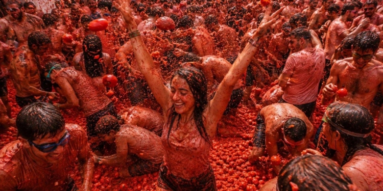 Participantes disfrutando de La Tomatina en Buñol, España, lanzando tomates.