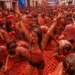 Participantes disfrutando de La Tomatina en Buñol, España, lanzando tomates.