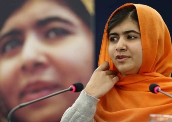 Malala Yousafzai hablando en una conferencia con un fondo difuminado.