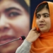 Malala Yousafzai hablando en una conferencia con un fondo difuminado.