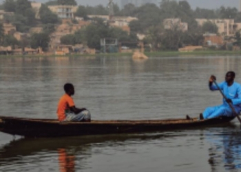 Un niño y un hombre en una piragua en el río Níger