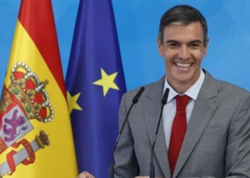 Pedro Sánchez sonriente en una conferencia de prensa con banderas de España y la UE