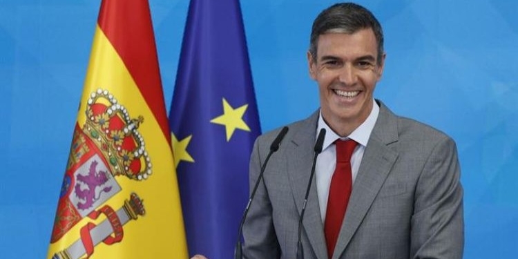 Pedro Sánchez sonriente en una conferencia de prensa con banderas de España y la UE