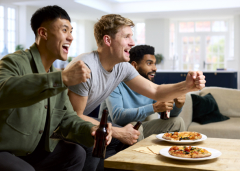 Grupo de amigos emocionados viendo un partido deportivo en casa
