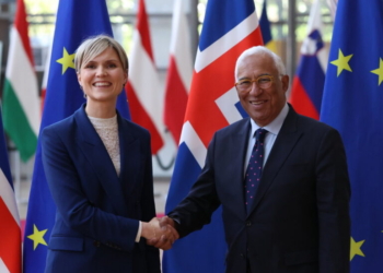 Dos personas estrechando manos frente a banderas de Islandia y la UE