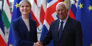 Dos personas estrechando manos frente a banderas de Islandia y la UE