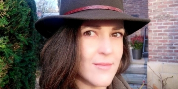 Retrato de Alicia Cocero con sombrero en un entorno urbano.