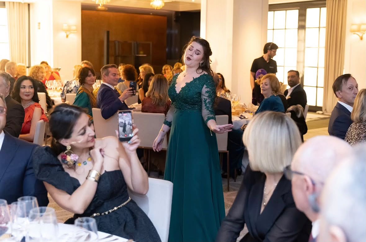 Mujer cantando en la cena de gala de AIDE con asistentes disfrutando